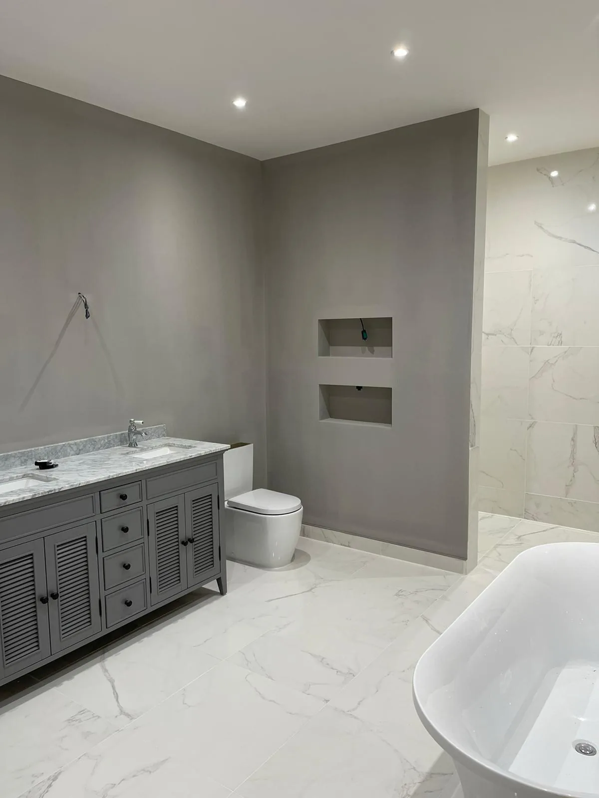 Bathroom finished in soft grey with marble tiling and a fitted vanity unit
