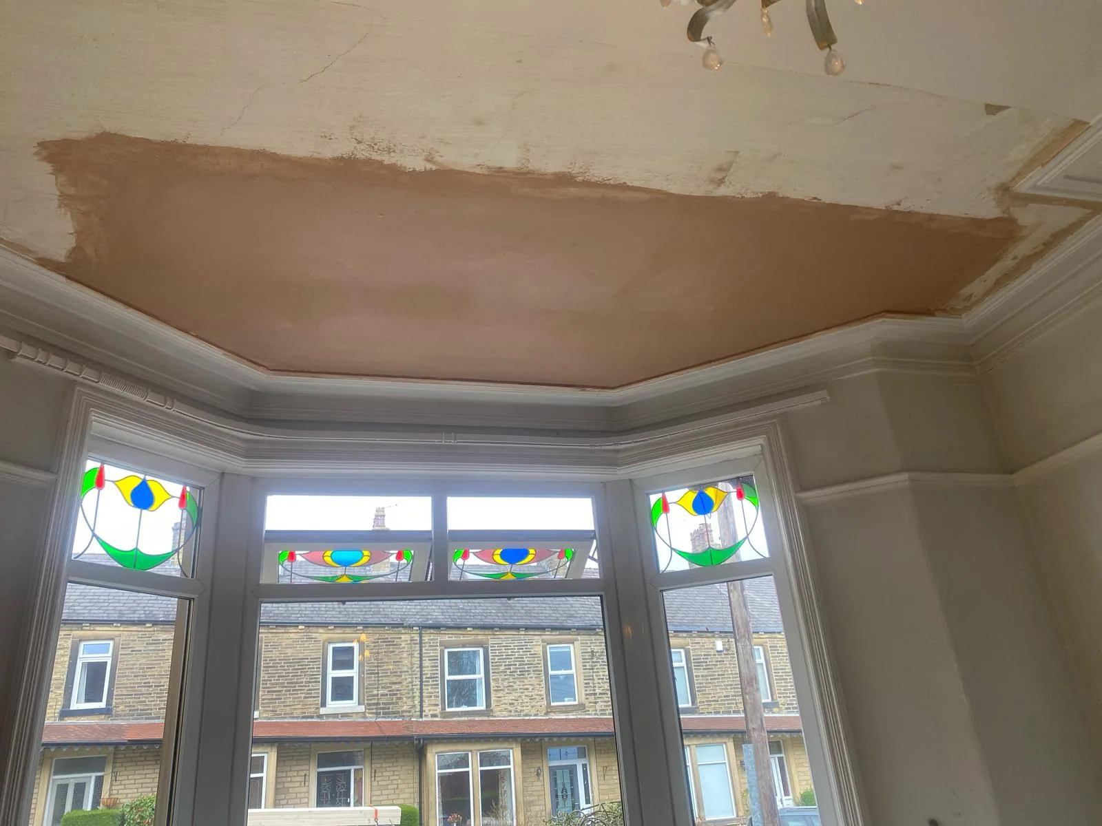 Bay window ceiling section freshly skimmed in pink plaster after water damage repair